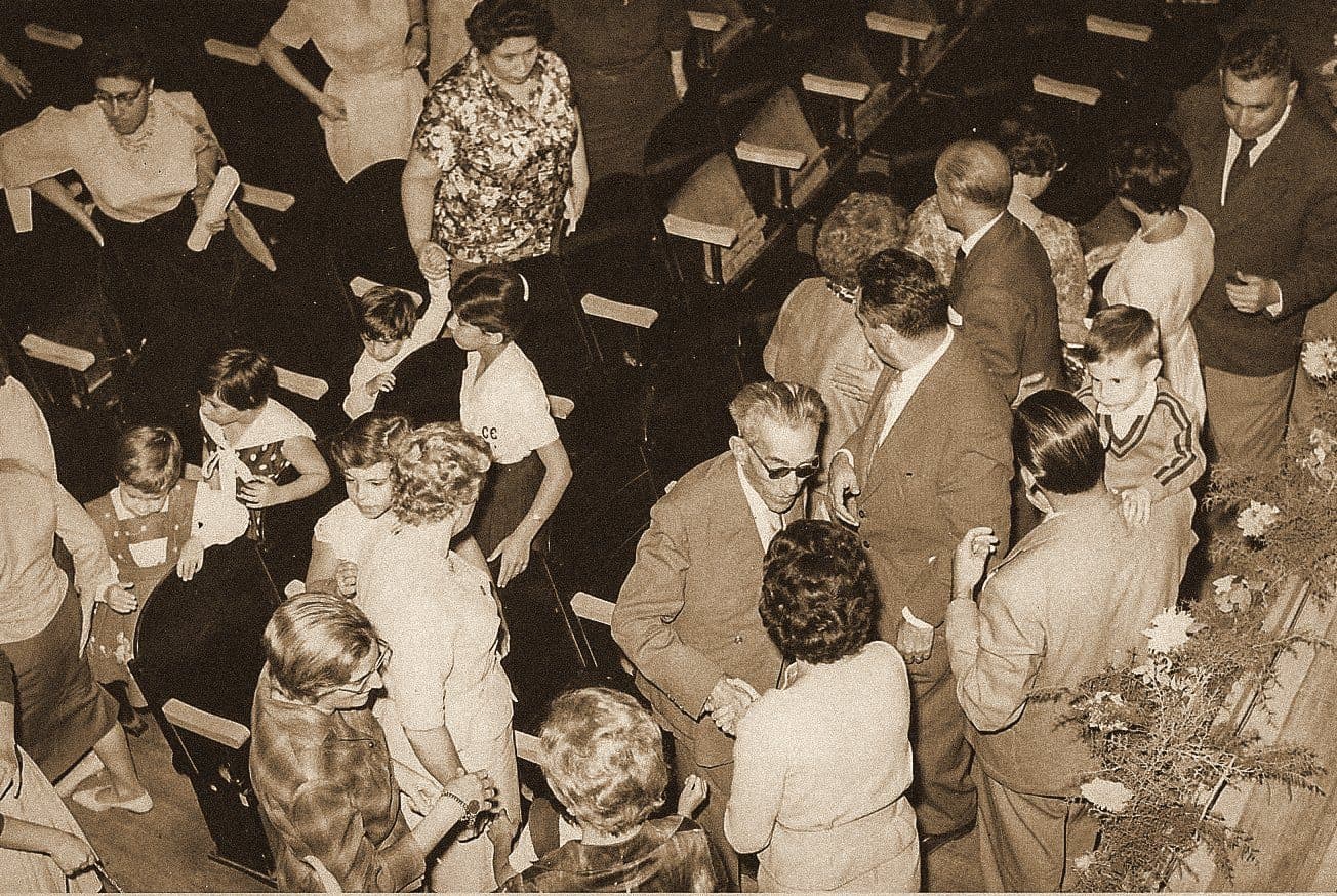 O público de época, em traje a rigor, diante do palco.