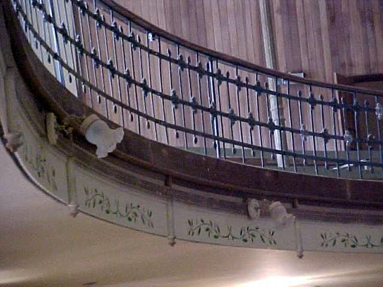 O gradil de ferro e a faixa pintada com ramos, na curva de um dos níveis da sala.