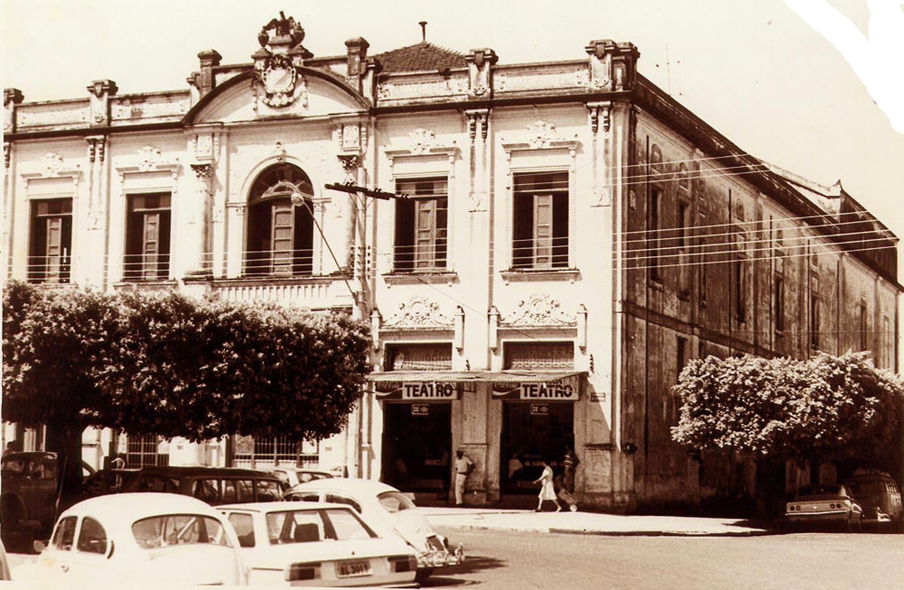 A fachada do Theatro com automóveis de época.