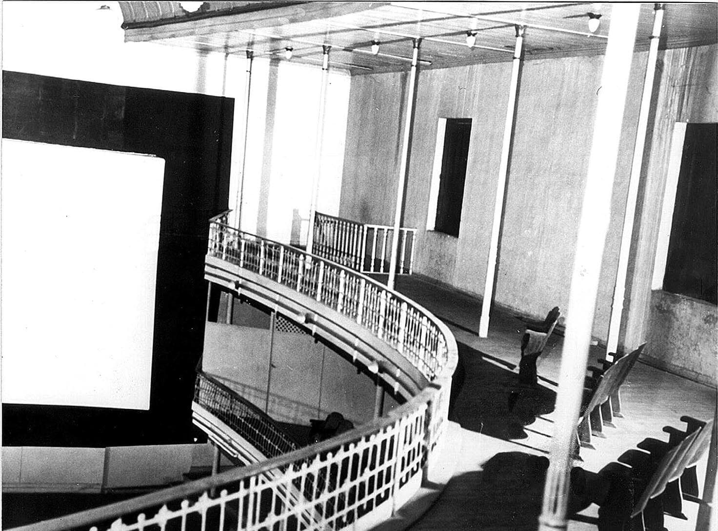 A tela do Cine Theatro montada na sala em ferradura — a galeria superior vazia diante da tela, no tempo do cinema.