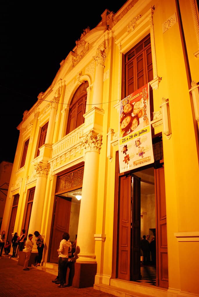 A fachada iluminada à noite, em noite de evento — o Theatro restaurado e em pleno uso.