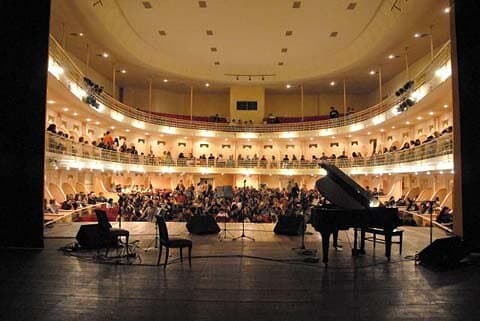 A sala lotada vista do palco, durante um concerto — o Theatro restaurado e em plena atividade.