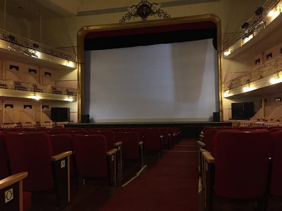 A sala em ferradura restaurada com a tela de cinema montada sobre o palco — o Theatro hoje também recebe sessões de cinema.