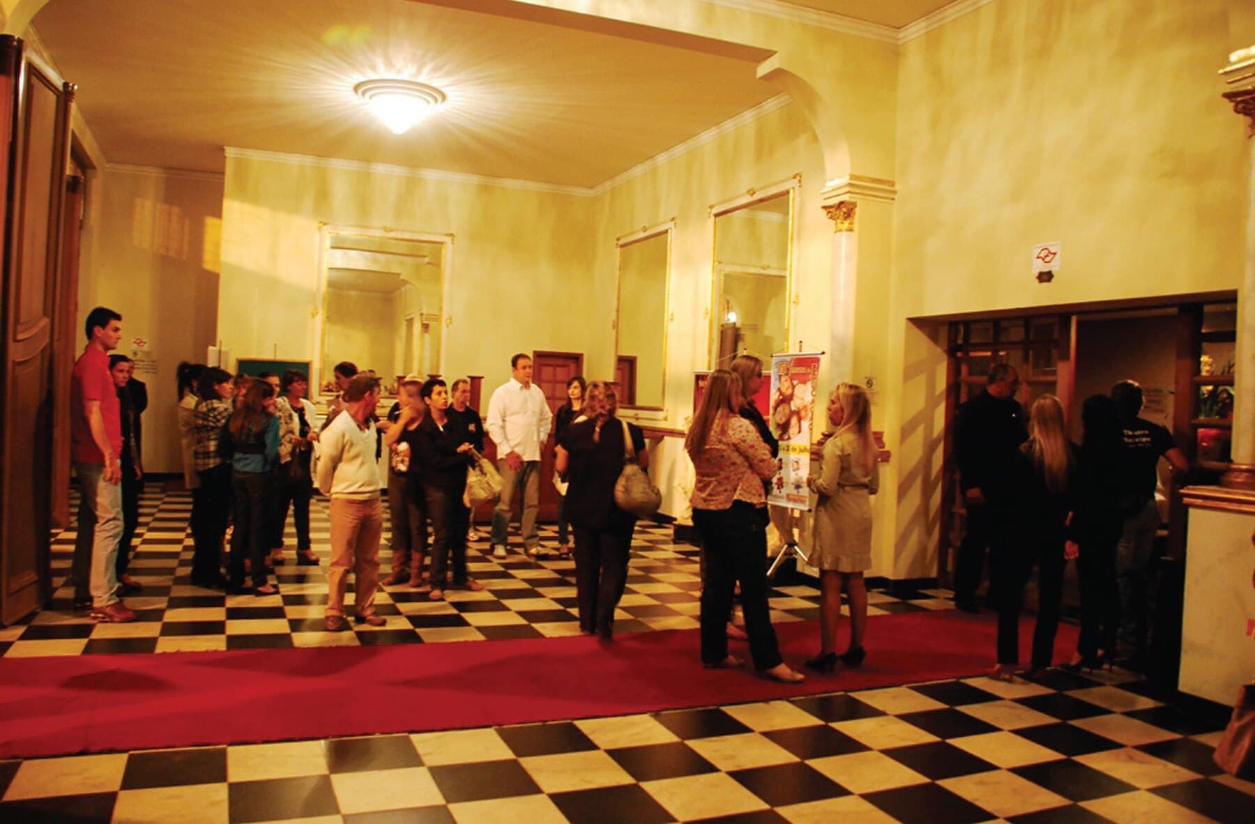 Visitantes diante das obras numa exposição montada no Theatro.