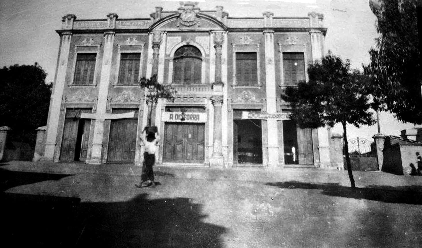 A fachada do Theatro, com uma figura solitária diante das portas, em registro antigo.