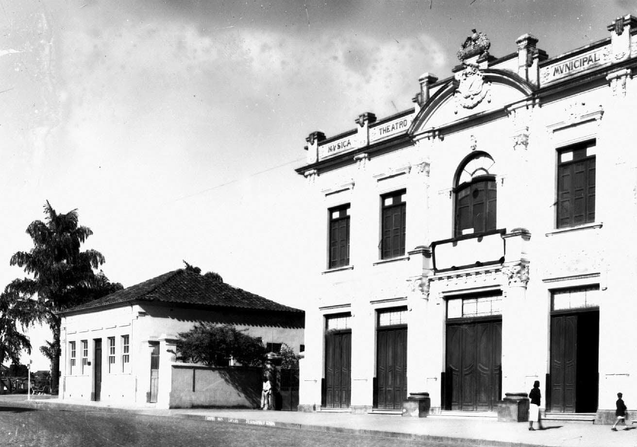 A fachada do Theatro ao lado das casas baixas do entorno, em registro antigo.